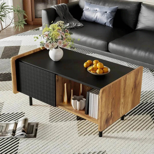 Rectangular modern coffee table with black top, wood sides, two drawers, and open storage compartments in a stylish living room setting